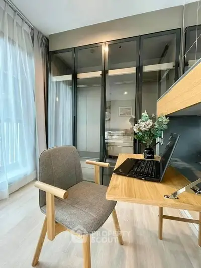 Modern study room with sleek desk, comfortable chair, and glass wardrobe in bright apartment.
