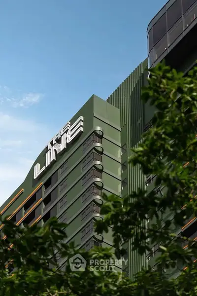 Modern green building exterior with sleek design and clear blue sky backdrop.