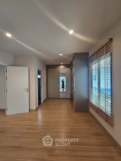 Spacious modern bedroom with wooden flooring and large windows