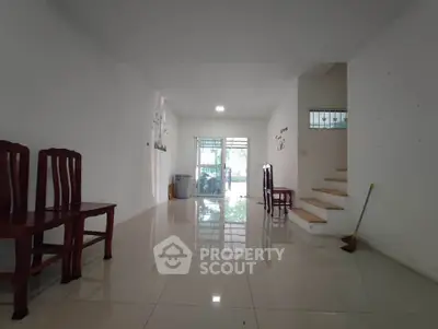 Spacious open-plan living area with glossy tiled floors and staircase, perfect for modern living.