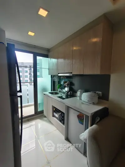 Modern kitchen with sleek cabinetry and appliances, featuring a balcony view in a stylish apartment.