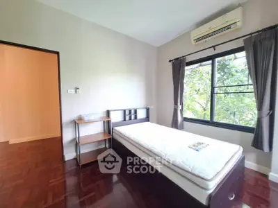 Cozy bedroom with single bed and large window overlooking greenery, perfect for peaceful living.