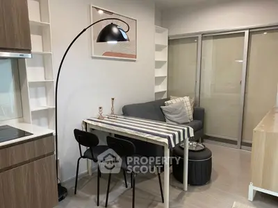 Modern living room with cozy sofa, stylish floor lamp, and compact dining area in open layout.