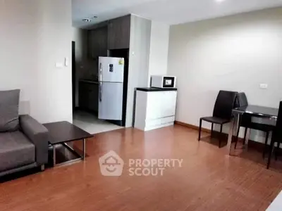 Modern living room with open kitchen and sleek furniture in a cozy apartment.