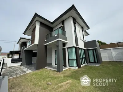 Modern two-story house with large windows and spacious lawn in suburban neighborhood.