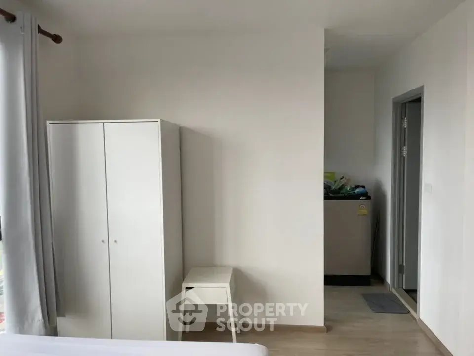 Modern minimalist bedroom with white wardrobe and washing machine corner.
