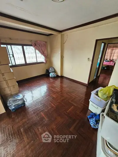 Spacious living room with wooden flooring and large windows in a cozy home.