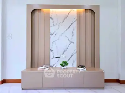 Elegant modern living room with stylish marble accent wall and built-in storage unit.
