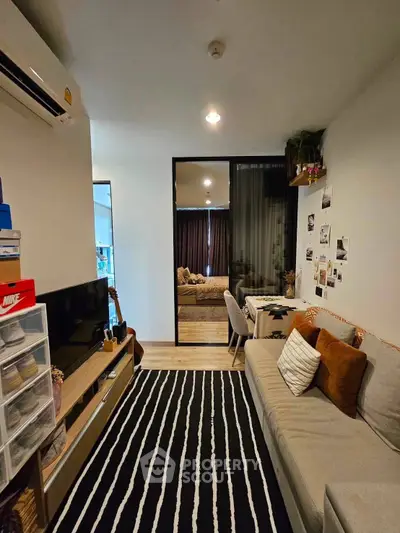 Cozy living room with modern decor and striped rug, featuring a comfortable sofa and wall-mounted TV.