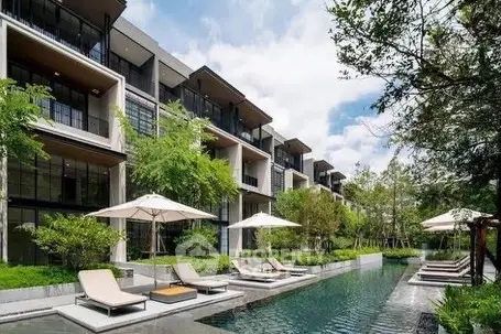 Luxurious modern apartment complex with poolside relaxation area and lush greenery.
