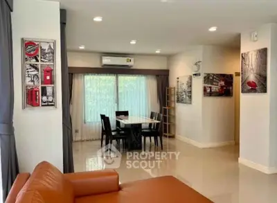 Spacious living room with modern decor and dining area, featuring elegant artwork and ample natural light.