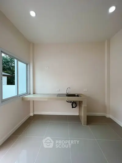 Modern minimalist kitchen with sleek tile flooring and large window for natural light.