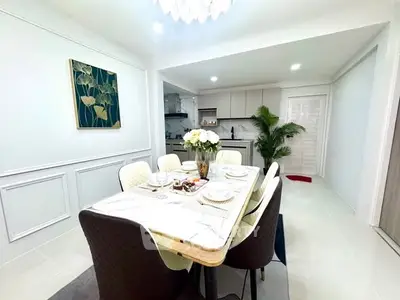 Elegant dining area with modern kitchen, featuring stylish decor and ample natural light.