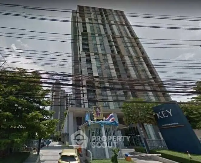 Modern high-rise condominium building with lush greenery and secure entrance in urban setting.