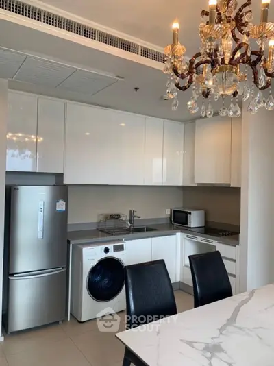 Modern kitchen with chandelier, sleek appliances, and elegant dining area