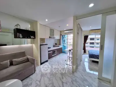 Modern open-plan apartment with sleek kitchen and cozy living area, featuring marble floors and natural light.