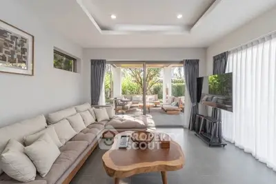 Spacious modern living room with natural light and garden view, featuring elegant decor and comfortable seating.