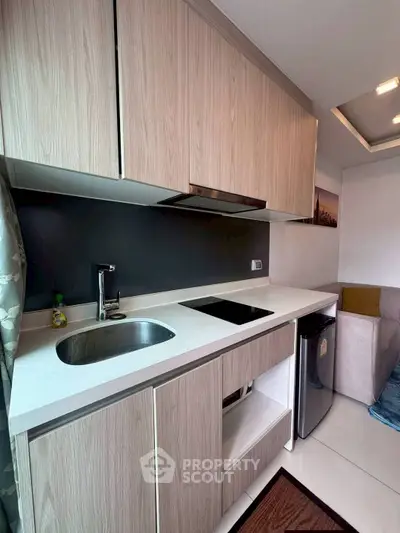 Modern compact kitchen with sleek cabinetry and integrated appliances in a stylish apartment.