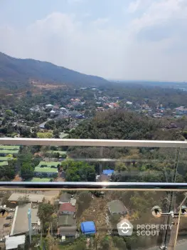 Stunning panoramic view from high-rise balcony overlooking lush green landscape and distant hills.