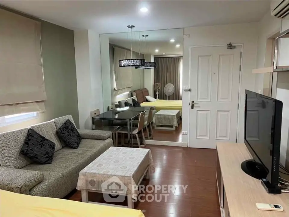 Cozy living room with modern decor and dining area, featuring a large mirror and flat-screen TV.