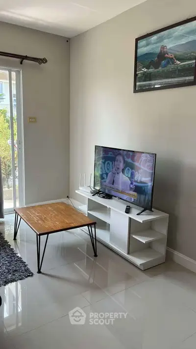 Modern living room with sleek TV stand, wall-mounted art, and natural light from large window.