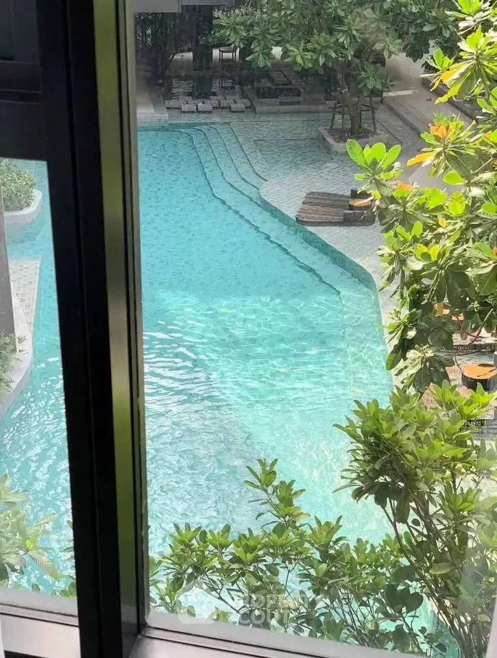Luxurious pool view from window with lush greenery and inviting lounge chairs.