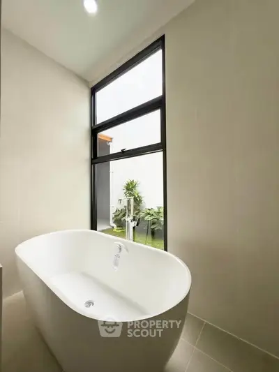 Luxurious bathroom with elegant freestanding bathtub and garden view, perfect for relaxation.