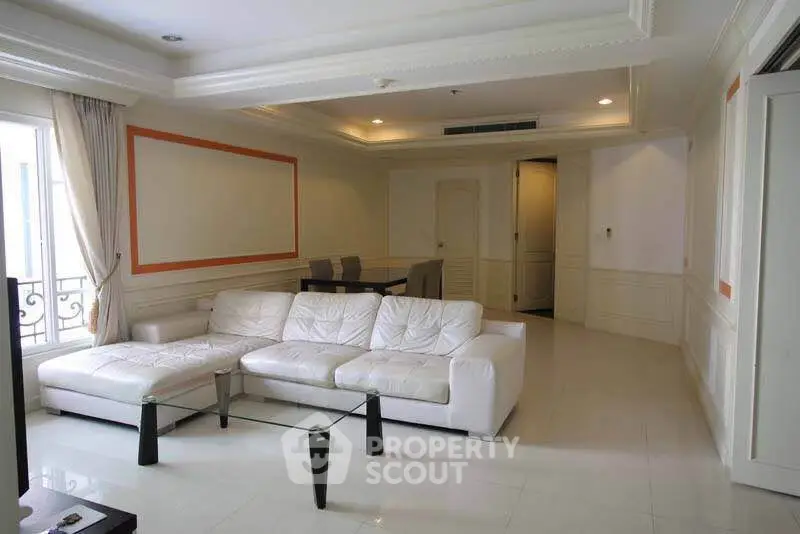 Spacious living room with elegant white sofa and dining area in luxury apartment.