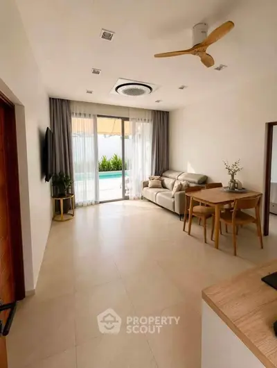 Spacious living room with modern decor and pool view, perfect for relaxation and entertainment.