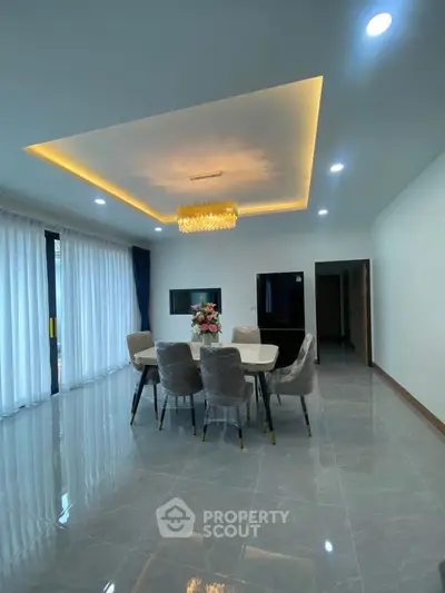 Elegant dining area with modern chandelier and floor-to-ceiling windows in a spacious living room.
