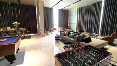 Luxurious living room with pool table and foosball, modern decor and ample seating.
