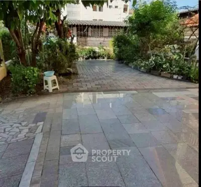Charming garden area with paved walkway and lush greenery, perfect for outdoor relaxation.
