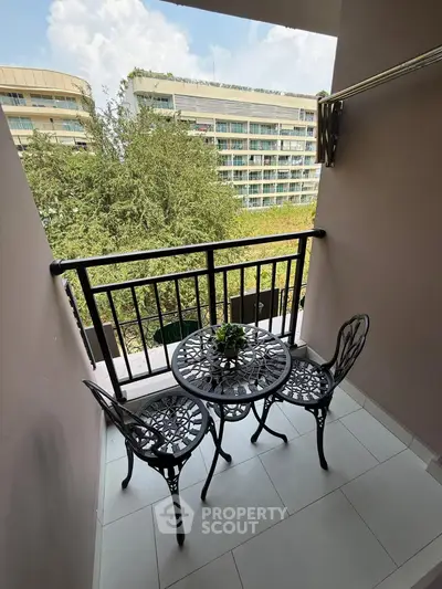 Charming balcony with elegant wrought iron furniture and lush green view, perfect for relaxation.