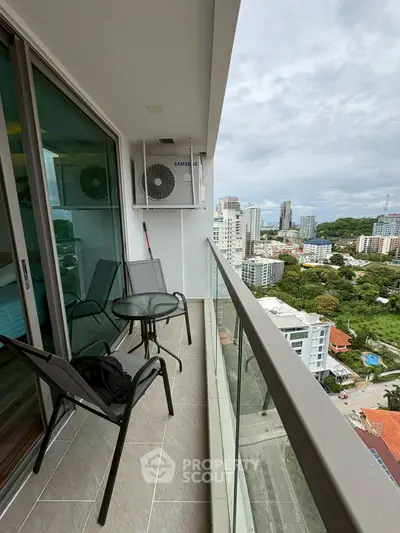 Modern balcony with city view, glass railing, and outdoor seating in high-rise building.