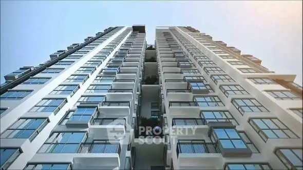 Modern high-rise building with sleek glass windows and balconies, showcasing urban architectural elegance.