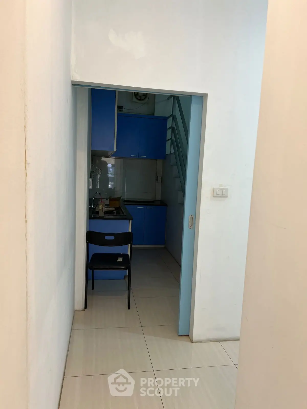 Compact kitchen with blue cabinets and a small dining area in a modern apartment.