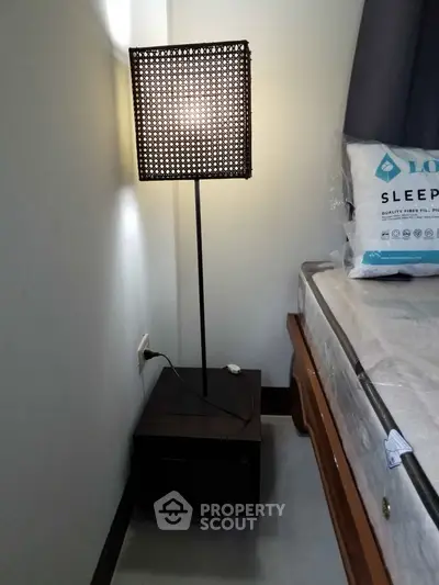 Cozy bedroom corner with stylish lamp and comfortable bed setup.