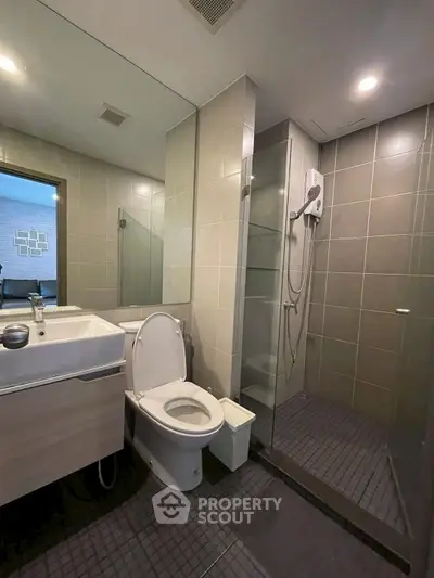Modern bathroom with glass shower enclosure and sleek fixtures in a contemporary apartment.