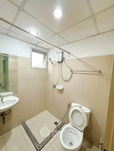 Modern bathroom with shower and toilet in minimalist design, featuring beige tiles and ceiling lights.
