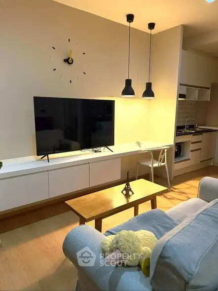 Modern living room with stylish decor and open kitchen layout, featuring a cozy sofa and wall-mounted TV.