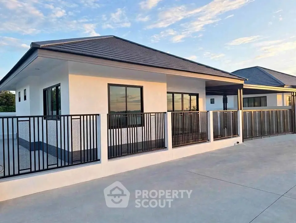 Modern single-story house with sleek design and spacious driveway under a clear blue sky.