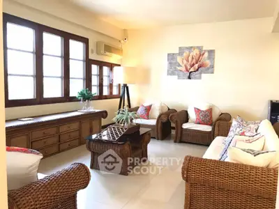 Charming living room with wicker furniture and large windows, perfect for relaxation and entertaining.