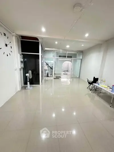 Spacious open-plan living area with tiled flooring and modern glass doors, perfect for versatile interior design.