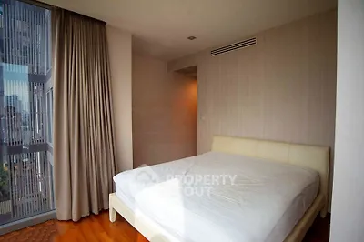 Spacious bedroom with large window offering city views and natural light.