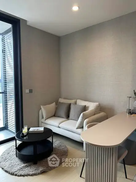 Modern living room with cozy sofa and stylish decor, adjacent to a balcony with natural light.