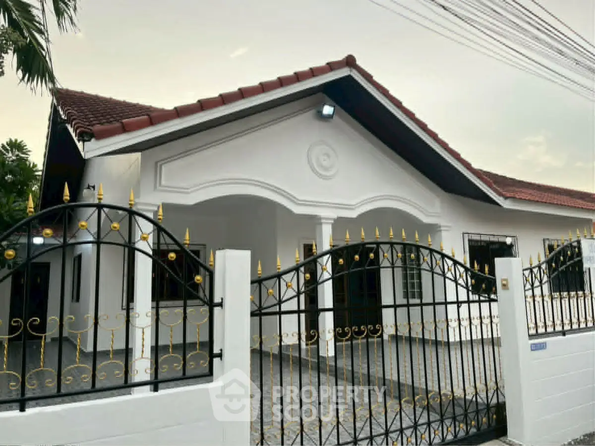 Charming single-story house with elegant wrought iron gate and red-tiled roof, perfect for family living.