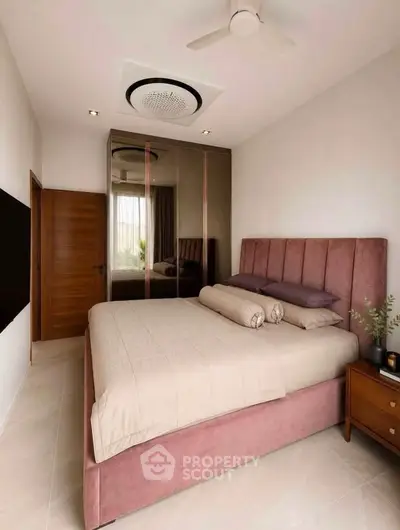 Elegant bedroom with plush bed, mirrored wardrobe, and modern ceiling fan in a cozy setting.