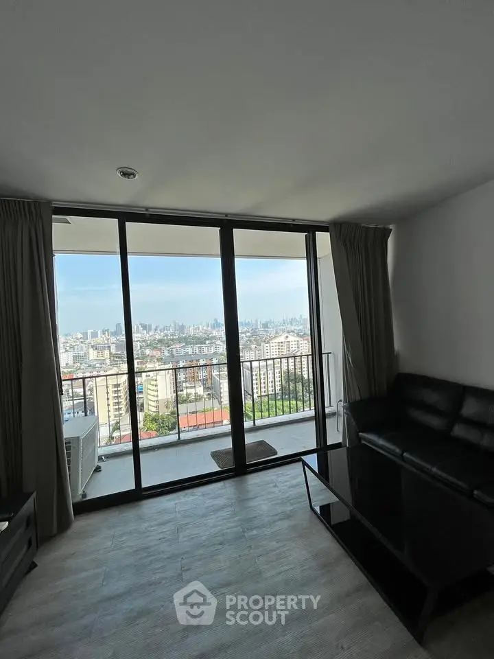 Spacious living room with stunning city view from large glass doors leading to a balcony.