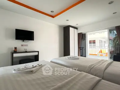 Modern bedroom with twin beds, wall-mounted TV, and balcony access in a stylish apartment.