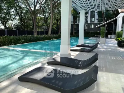Luxurious outdoor pool area with stylish loungers and lush greenery in a modern residential complex.